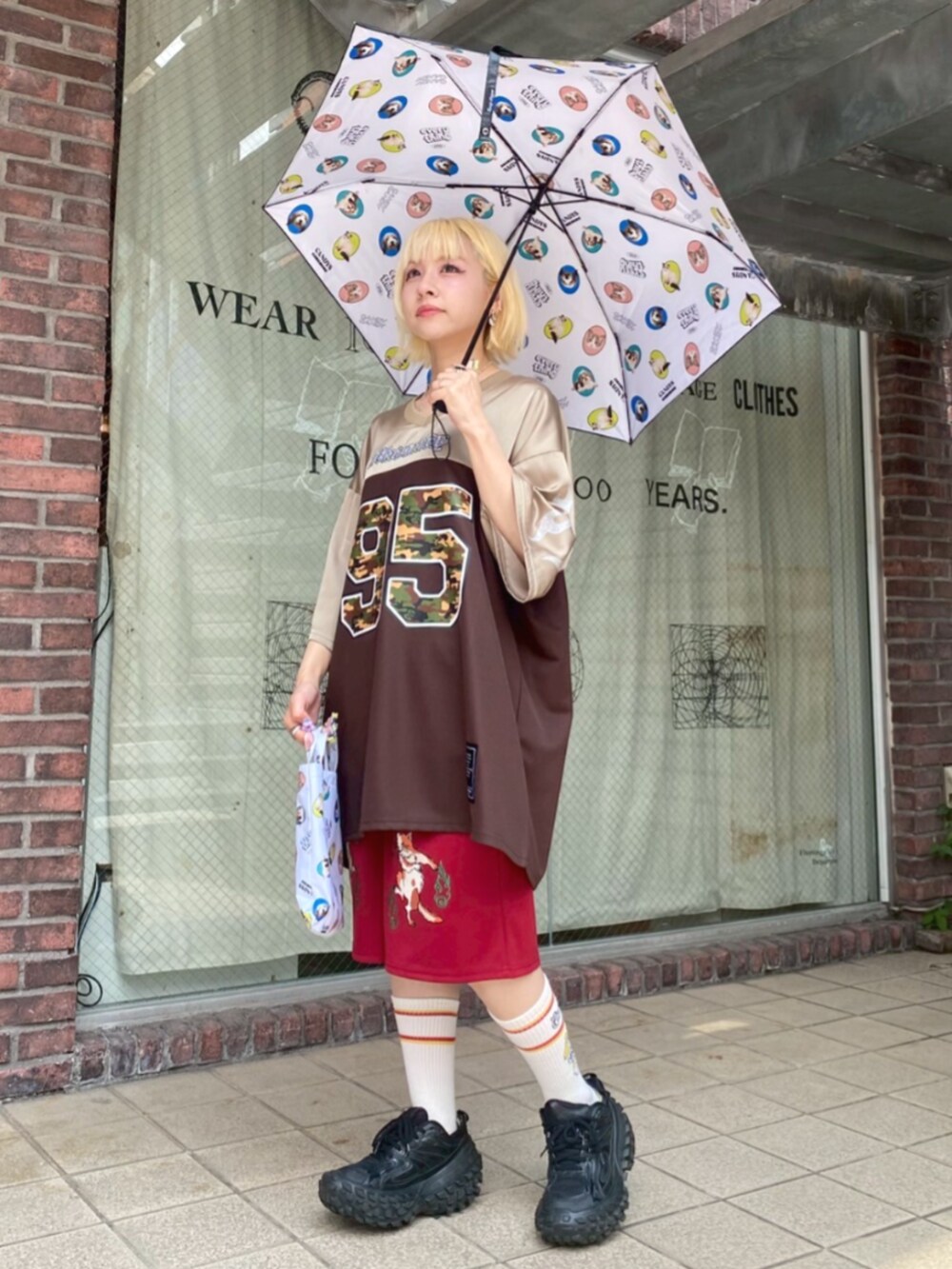 ブラウン系のTシャツ/カットソー、レッド系のその他パンツ、ブラック系の折りたたみ傘を着用したレディースの夏コーディネートの3枚目の写真