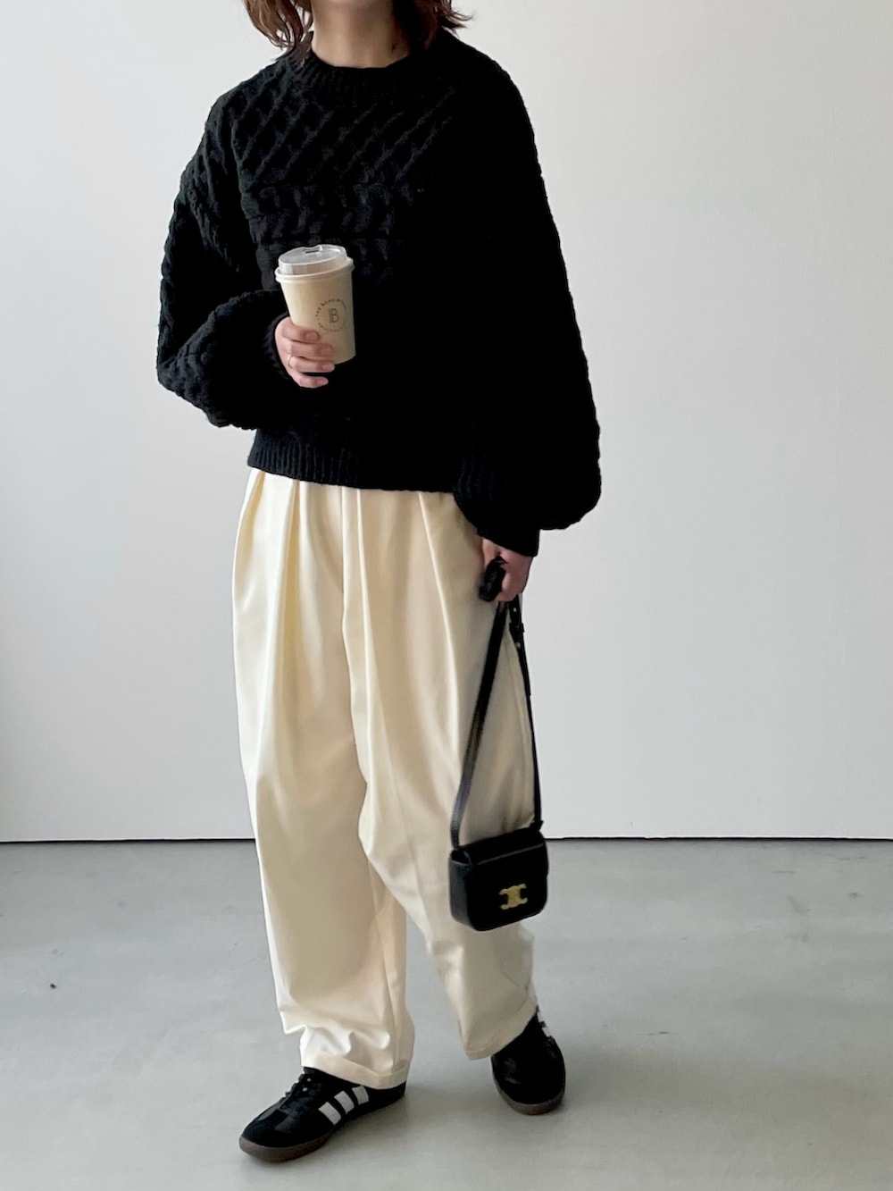 ブラック系のニット/セーター、ホワイト系のその他パンツ、ブラック系のスニーカーを着用したレディースの冬コーディネートの2枚目の写真