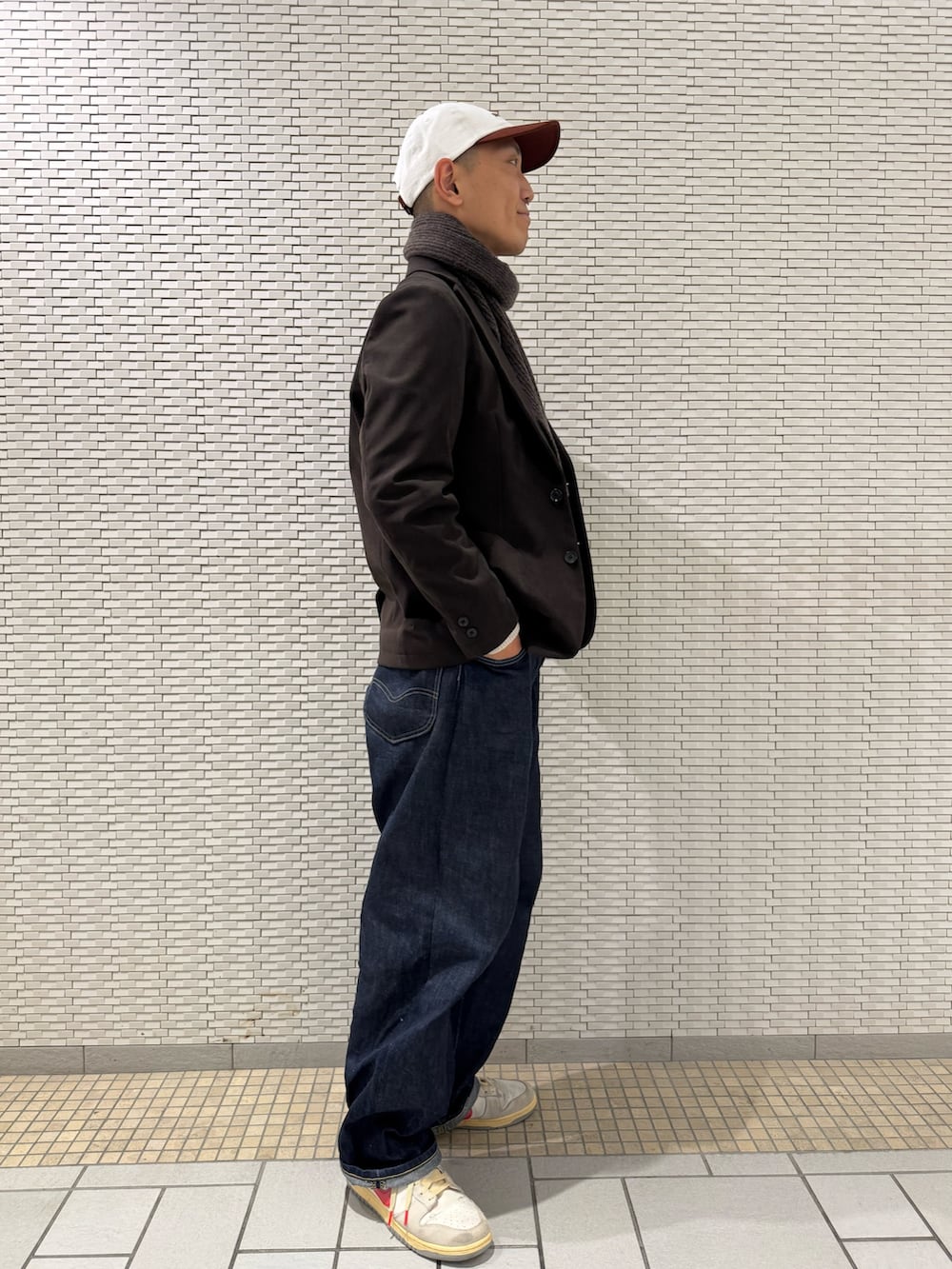 ブラウン系のスーツジャケット、ホワイト系のニット/セーター、ブラウン系のマフラーを着用したメンズの冬コーディネートの2枚目の写真