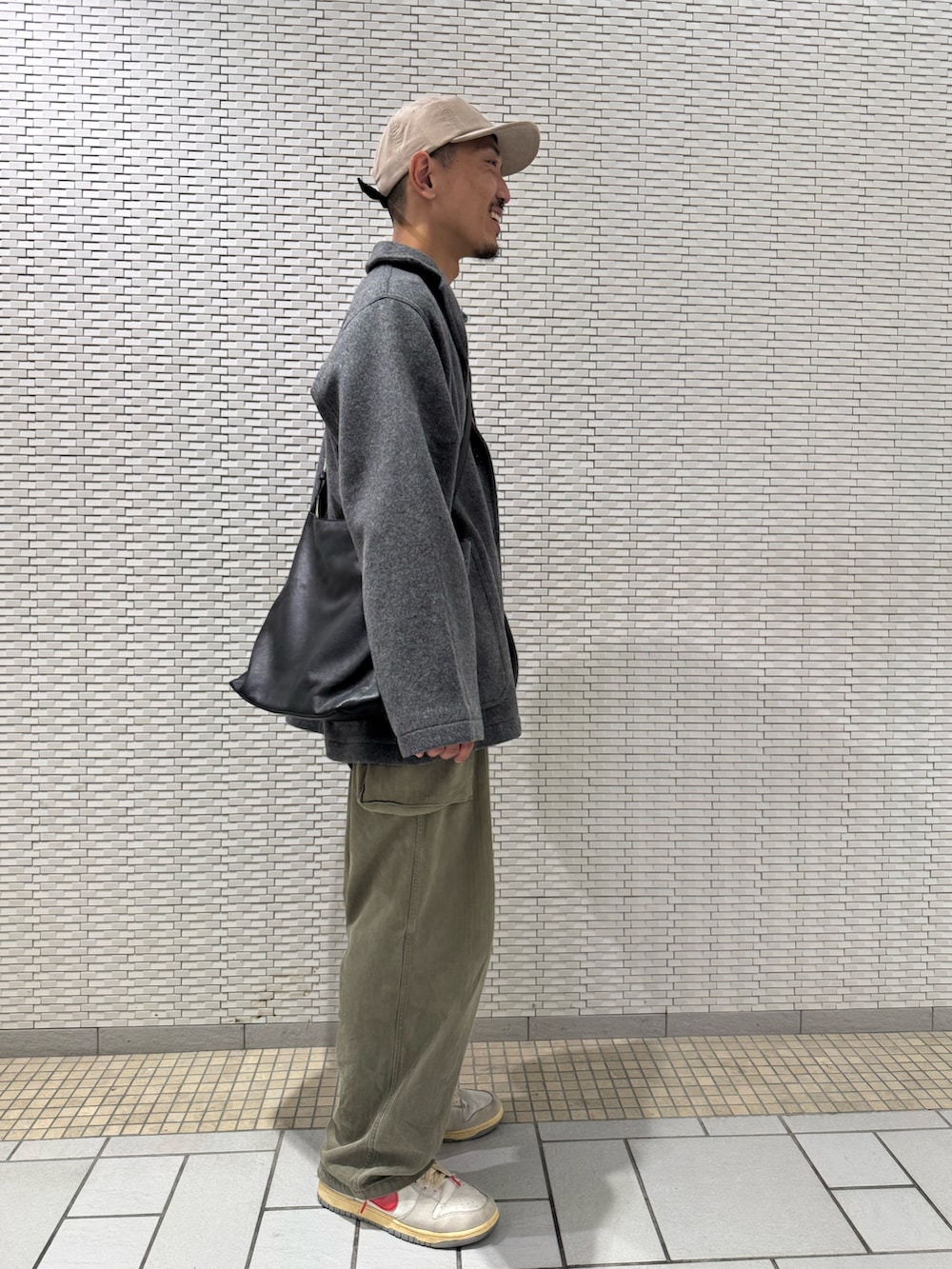 グレー系のテーラードジャケット、ベージュ系のキャップを着用したメンズの秋コーディネートの2枚目の写真