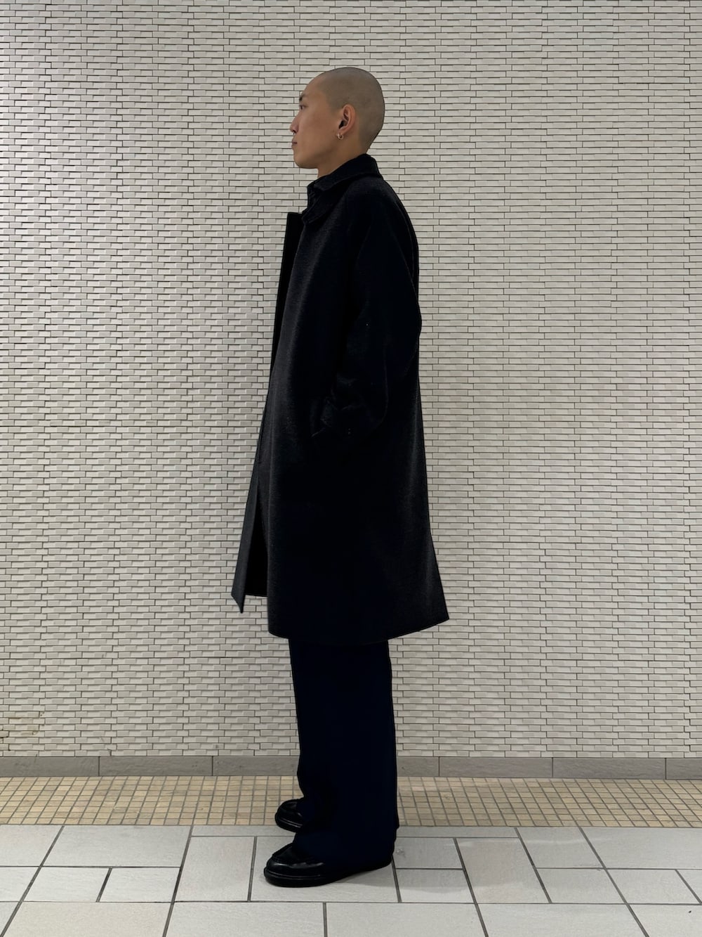 グレー系のステンカラーコート、ブルー系のベストを着用したメンズの秋コーディネートの2枚目の写真