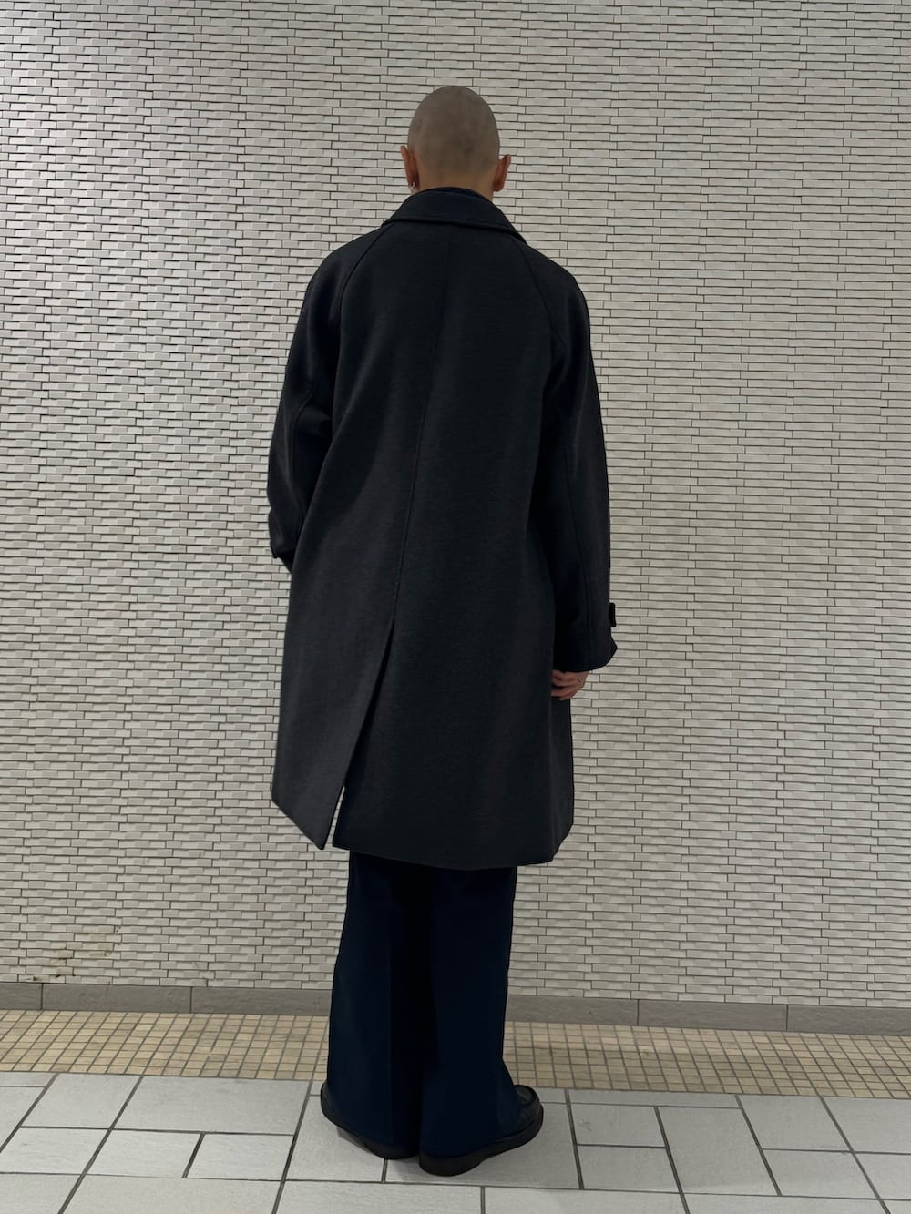 グレー系のステンカラーコート、ブルー系のベストを着用したメンズの秋コーディネートの3枚目の写真