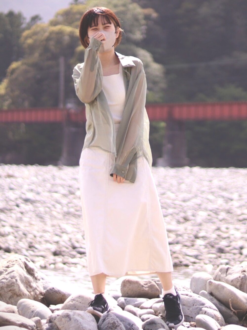 グリーン系のシャツ/ブラウス、ホワイト系のスカート、ブラック系のスニーカーを着用したレディースの春コーディネートの2枚目の写真