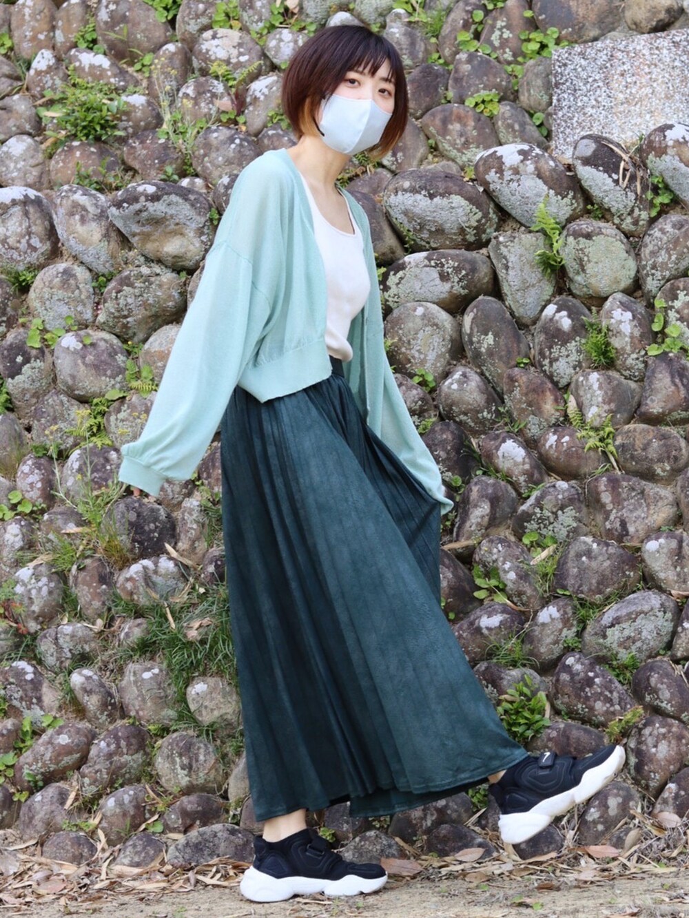 ホワイト系のタンクトップ、グリーン系のスカート、ブラック系のスニーカーを着用したレディースの春コーディネートの2枚目の写真