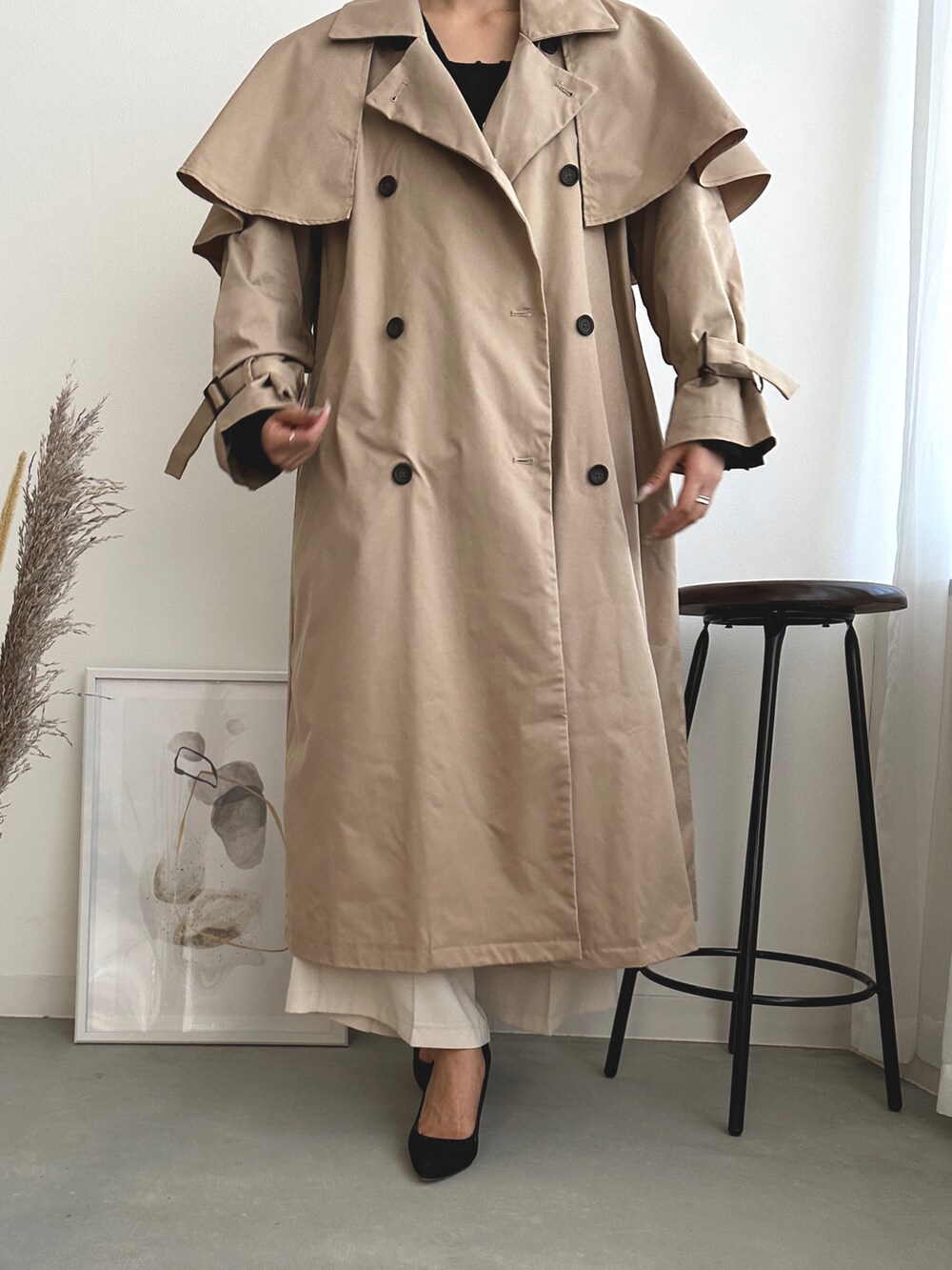 ブラック系のベスト、ベージュ系のトレンチコート、ホワイト系のスラックスを着用したレディースの秋コーディネートの3枚目の写真