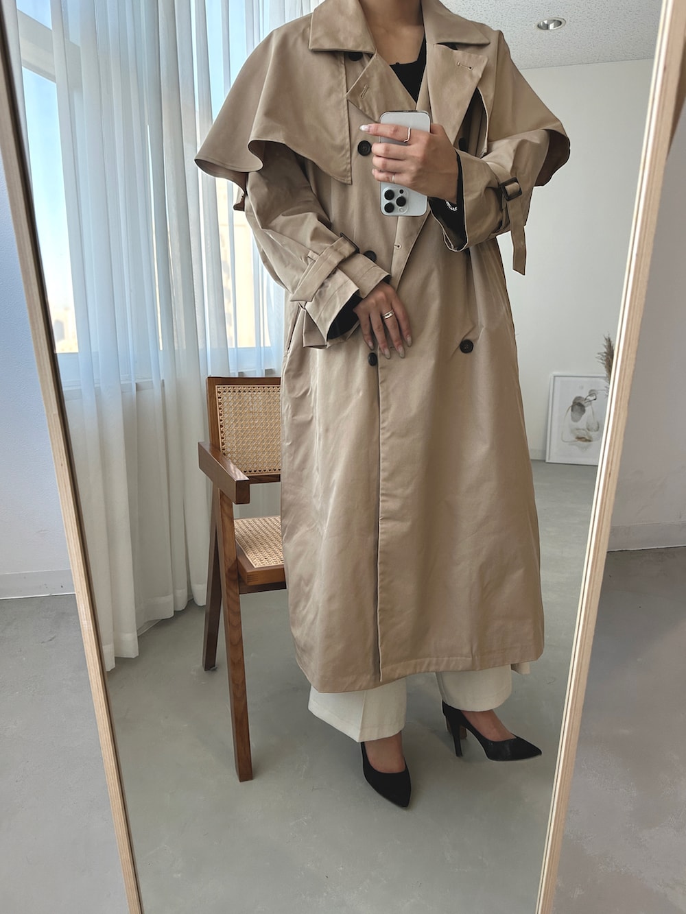 ブラック系のベスト、ベージュ系のトレンチコート、ホワイト系のスラックスを着用したレディースの秋コーディネートの2枚目の写真