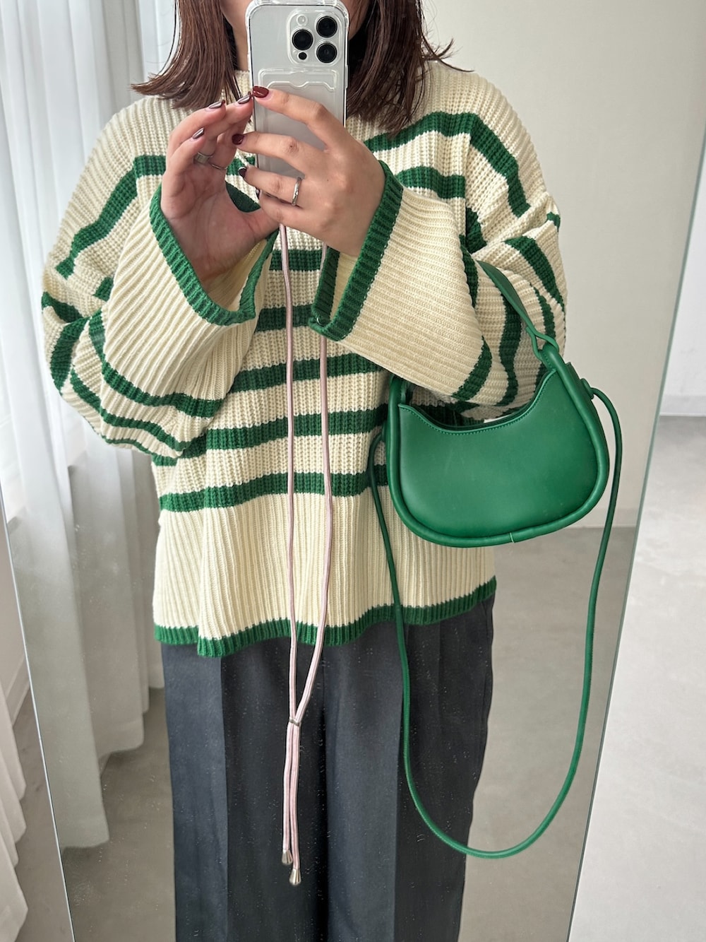 グリーン系のニット/セーター、グレー系のスラックスを着用したレディースの秋コーディネートの2枚目の写真