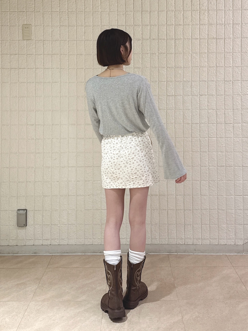 ピンク系のスカート、グレー系のTシャツ/カットソー、イエロー系のブーツを着用したレディースの冬コーディネートの2枚目の写真