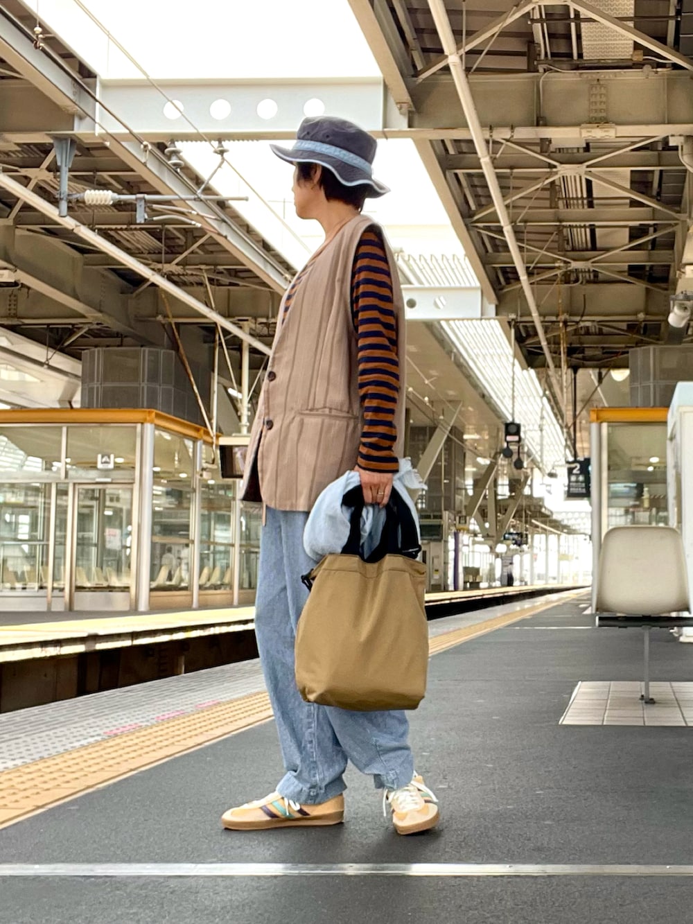 ブラウン系のTシャツ/カットソー、ベージュ系のベスト、ブルー系のデニムパンツを着用したレディースの春コーディネートの2枚目の写真