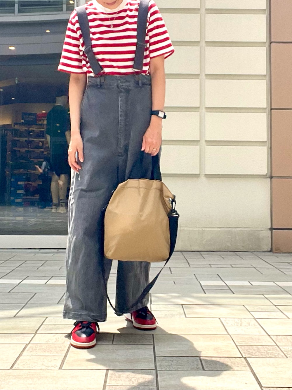 レッド系のTシャツ/カットソー、レッド系のスニーカー、グレー系のオールインワン・サロペットを着用したレディースの夏コーディネートの3枚目の写真