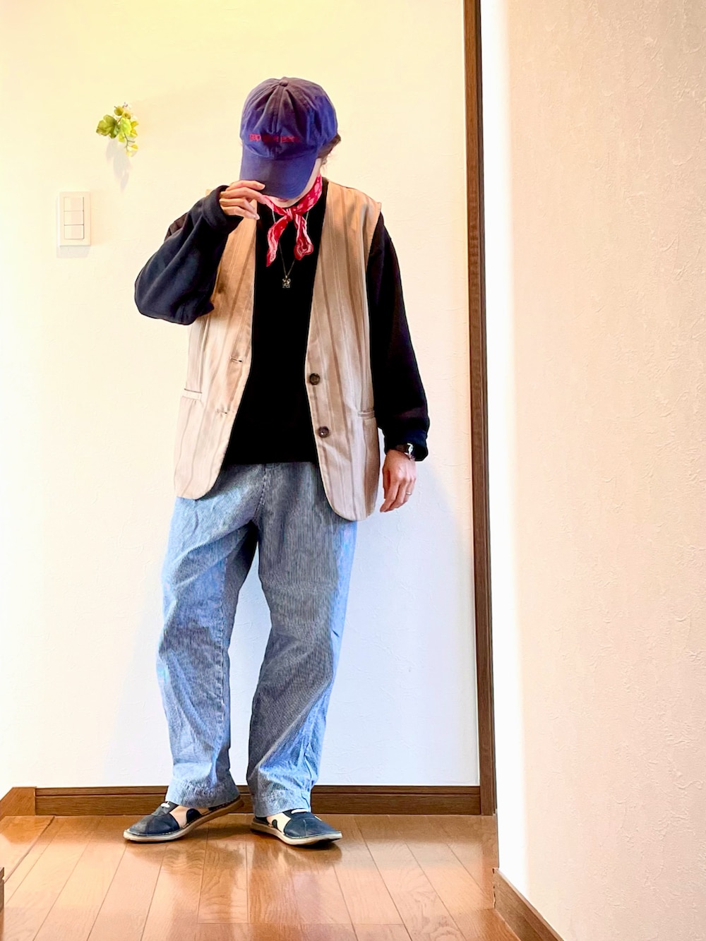 ブラック系のスウェット、ベージュ系のベスト、ブルー系のデニムパンツを着用したレディースの春コーディネートの3枚目の写真