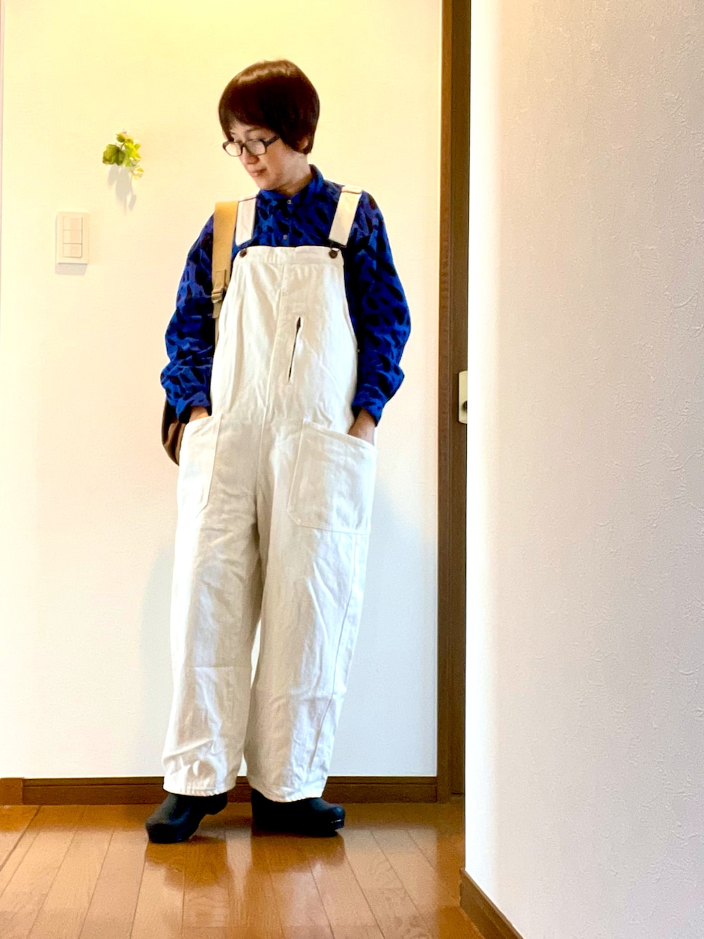 ブルー系のシャツ/ブラウス、ホワイト系のサロペット/オーバーオール、ブラック系のスリッポンを着用したレディースの春コーディネートの2枚目の写真