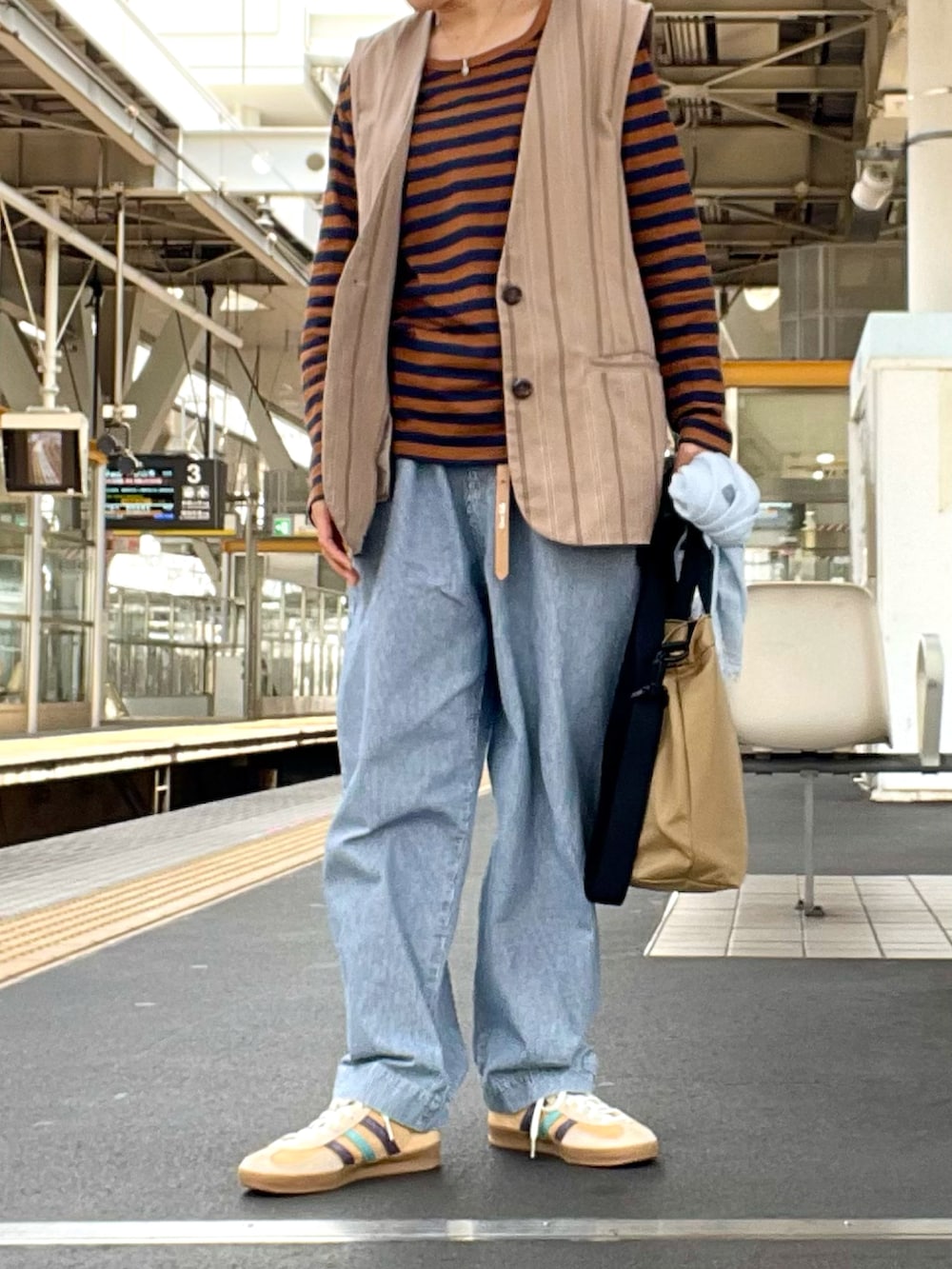 ブラウン系のTシャツ/カットソー、ベージュ系のベスト、ブルー系のデニムパンツを着用したレディースの春コーディネートの3枚目の写真