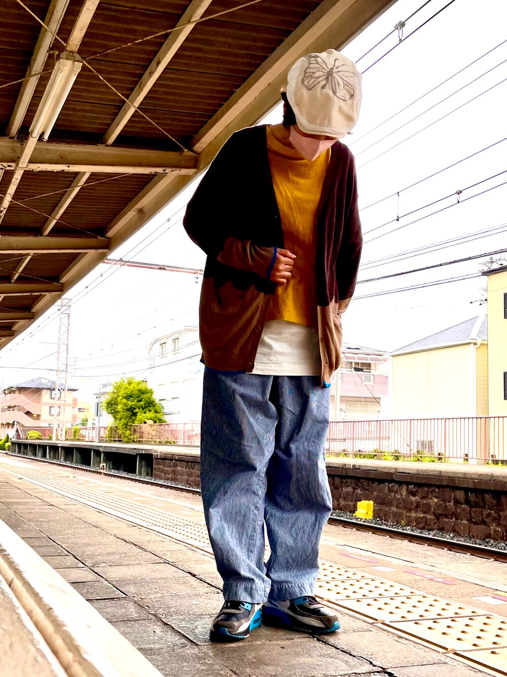 ブラウン系のカーディガン/ボレロ、イエロー系のTシャツ/カットソー、ブルー系のデニムパンツを着用したレディースの春コーディネートの3枚目の写真