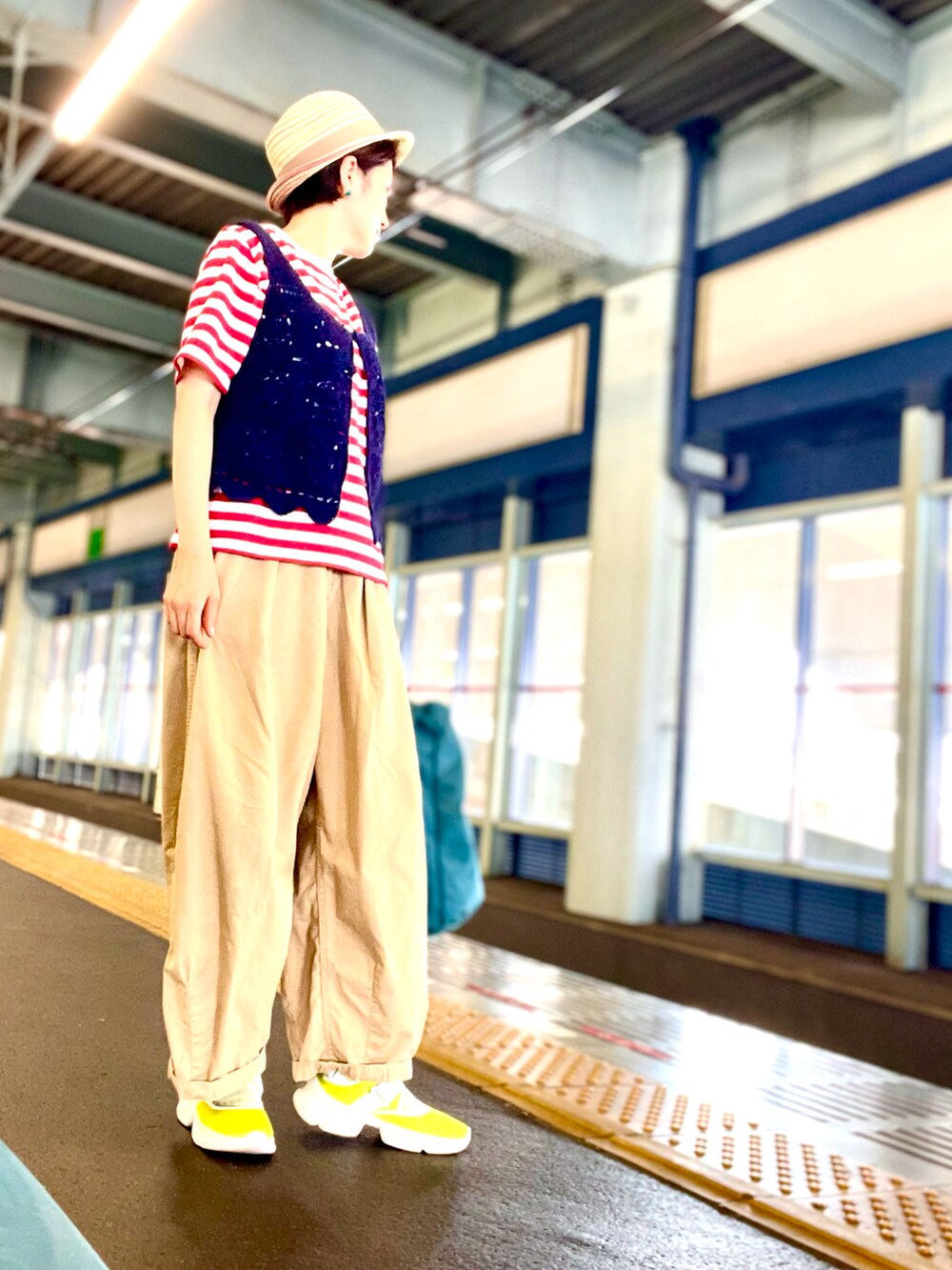 ブルー系のベスト、レッド系のTシャツ/カットソー、ベージュ系のチノパンツを着用したレディースの秋コーディネートの3枚目の写真