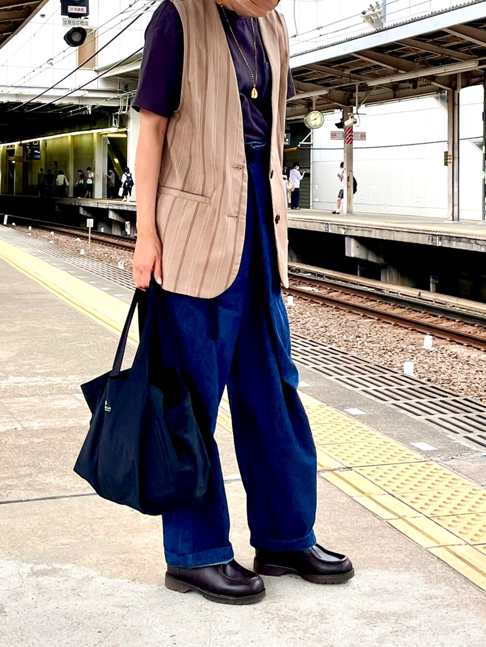 ベージュ系のベスト、グレー系のTシャツ/カットソー、ブルー系のデニムパンツを着用したレディースの秋コーディネートの3枚目の写真
