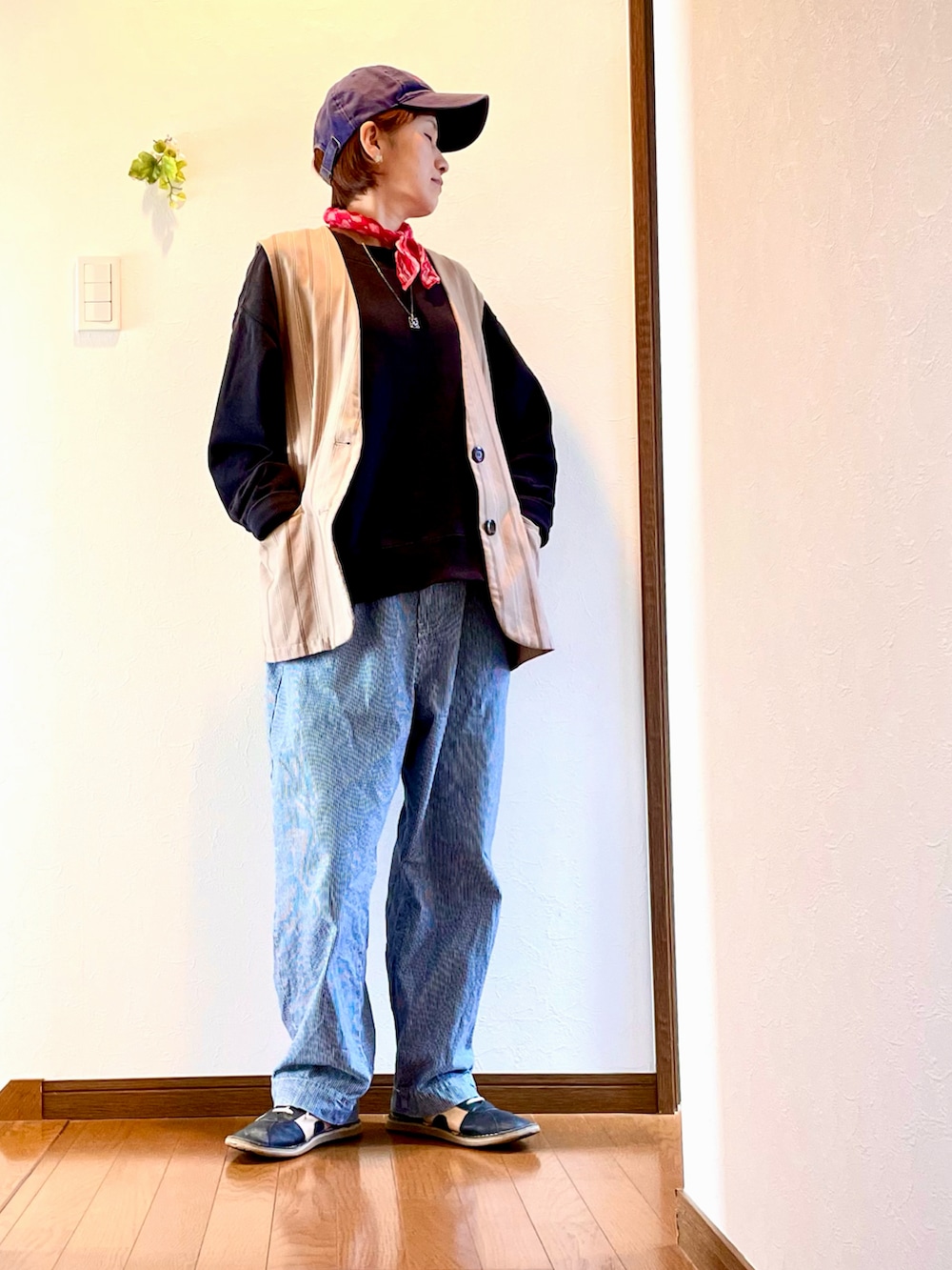 ブラック系のスウェット、ベージュ系のベスト、ブルー系のデニムパンツを着用したレディースの春コーディネートの2枚目の写真