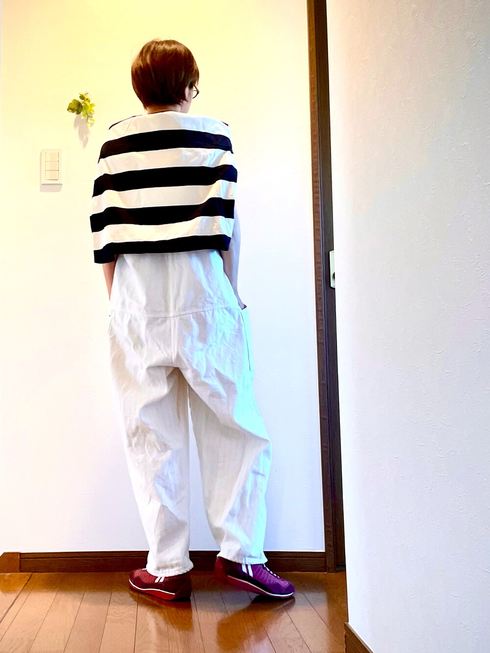 ホワイト系のサロペット/オーバーオール、グリーン系のTシャツ/カットソー、レッド系のスニーカーを着用したレディースの秋コーディネートの4枚目の写真