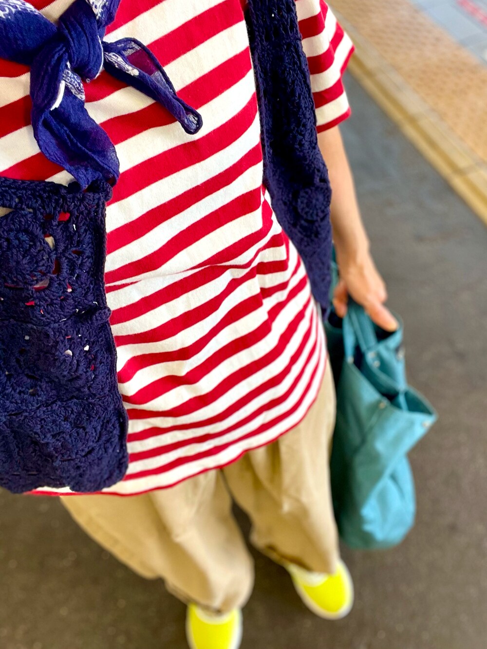 ブルー系のベスト、レッド系のTシャツ/カットソー、ベージュ系のチノパンツを着用したレディースの秋コーディネートの4枚目の写真