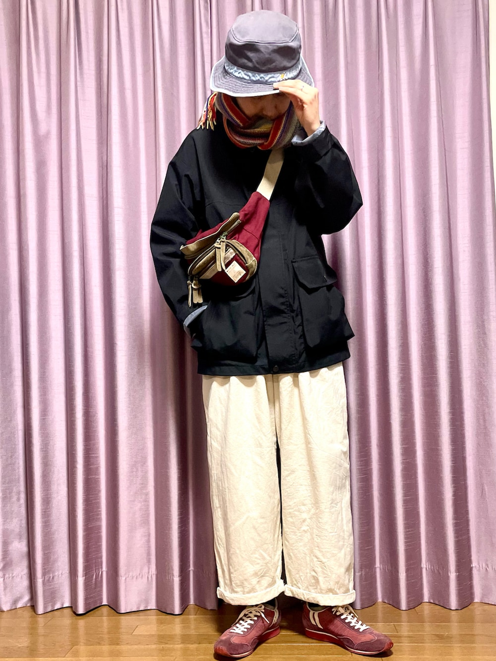 ブラック系のマウンテンパーカー、ホワイト系のその他パンツ、レッド系のスニーカーを着用したレディースの冬コーディネートの2枚目の写真