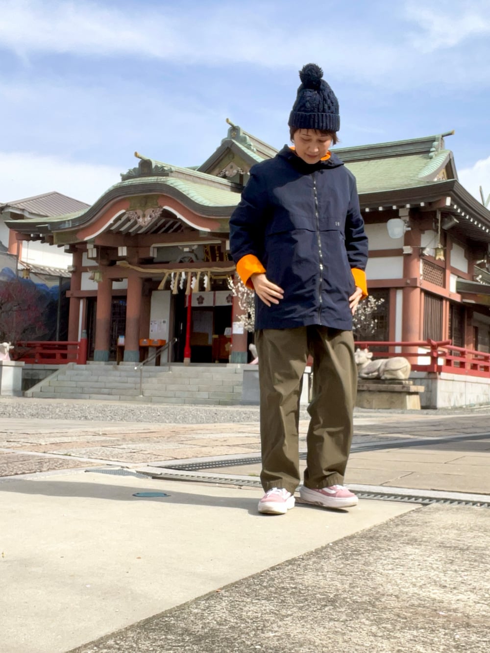 グリーン系のその他パンツ、オレンジ系のマウンテンパーカー、ピンク系のスニーカーを着用したレディースの春コーディネートの3枚目の写真