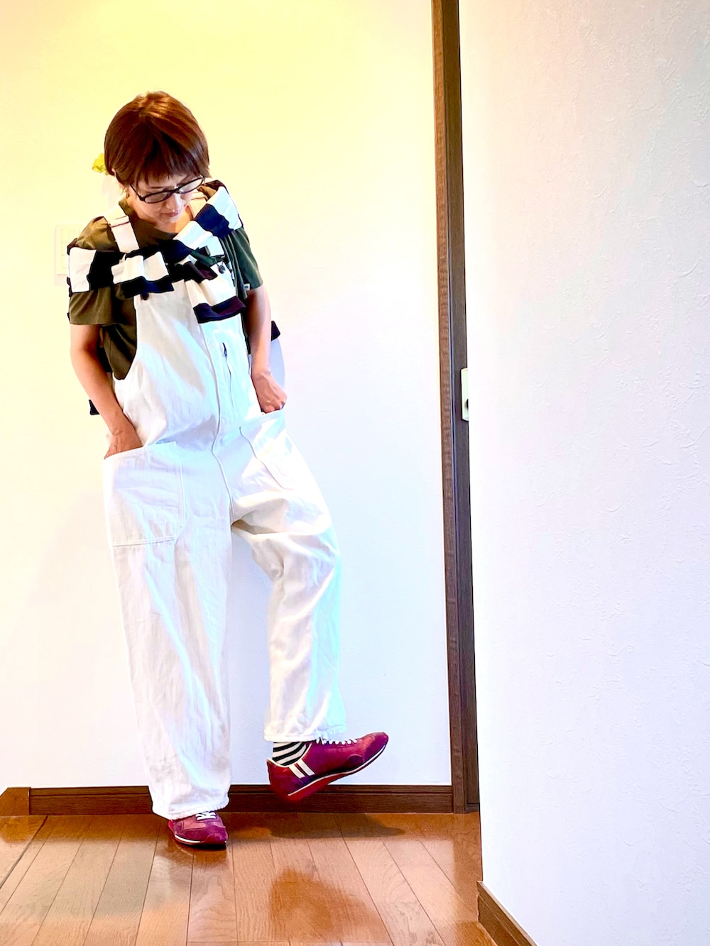 ホワイト系のサロペット/オーバーオール、グリーン系のTシャツ/カットソー、レッド系のスニーカーを着用したレディースの秋コーディネートの3枚目の写真