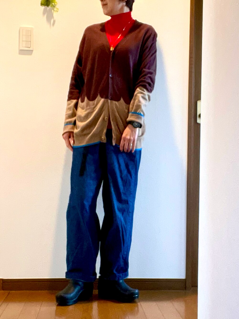 ブラウン系のカーディガン/ボレロ、レッド系のニット/セーター、ブルー系のデニムパンツを着用したレディースの冬コーディネートの2枚目の写真