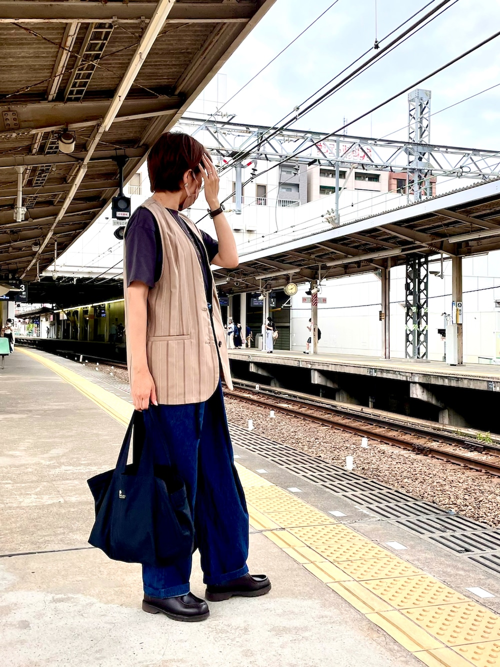 ベージュ系のベスト、グレー系のTシャツ/カットソー、ブルー系のデニムパンツを着用したレディースの秋コーディネートの2枚目の写真