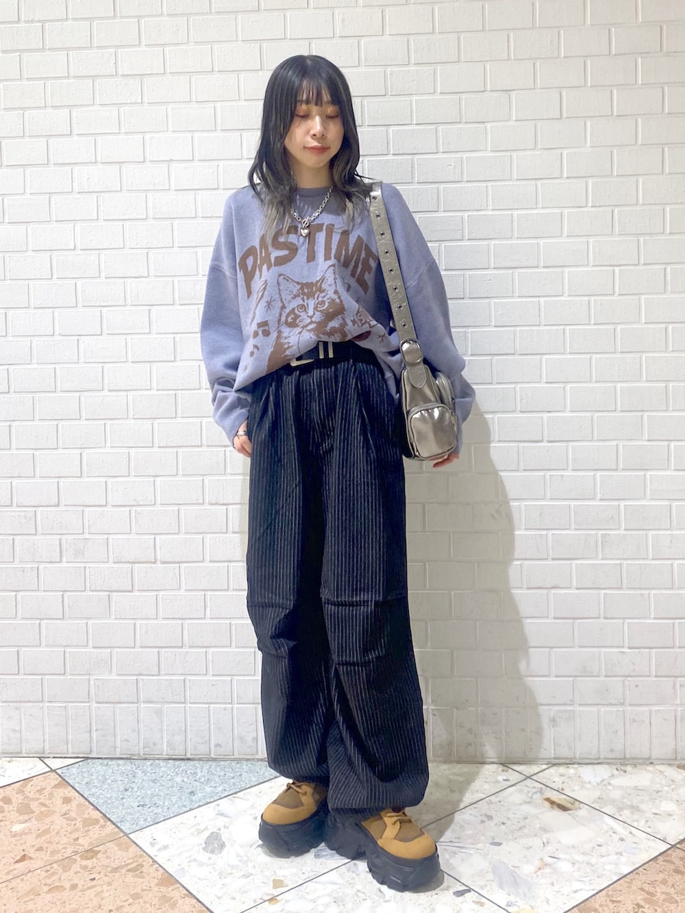 ブラウン系のブーツ、ブラック系のデニムパンツ、シルバー系のショルダーバッグを着用したレディースの冬コーディネートの6枚目の写真