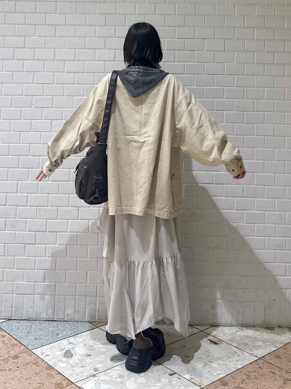 ブラウン系のブーツ、ブラック系のキャミソール、ベージュ系のスカートを着用したレディースの春コーディネートの6枚目の写真