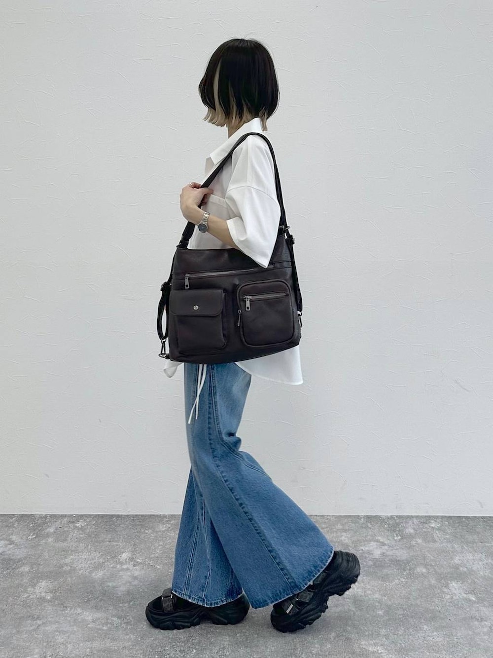 ブルー系のデニムパンツ、ブラック系のショルダーバッグ、グレー系のサンダルを着用したレディースの春コーディネートの5枚目の写真