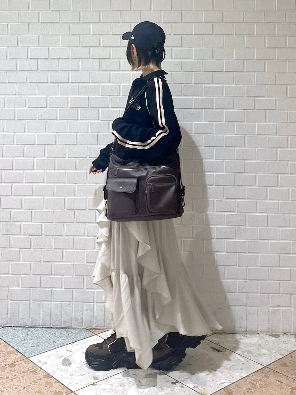 ブラウン系のブーツ、ブラック系のキャミソール、ベージュ系のスカートを着用したレディースの春コーディネートの5枚目の写真