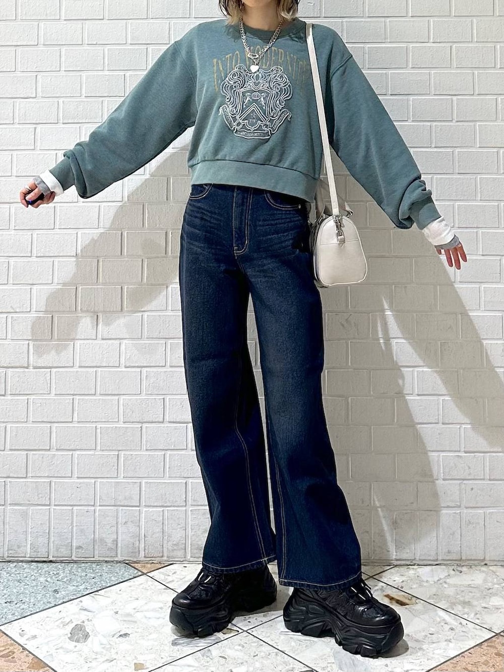 ブラック系のスニーカー、ブルー系のスラックス、ホワイト系のボストンバッグを着用したレディースの冬コーディネートの2枚目の写真