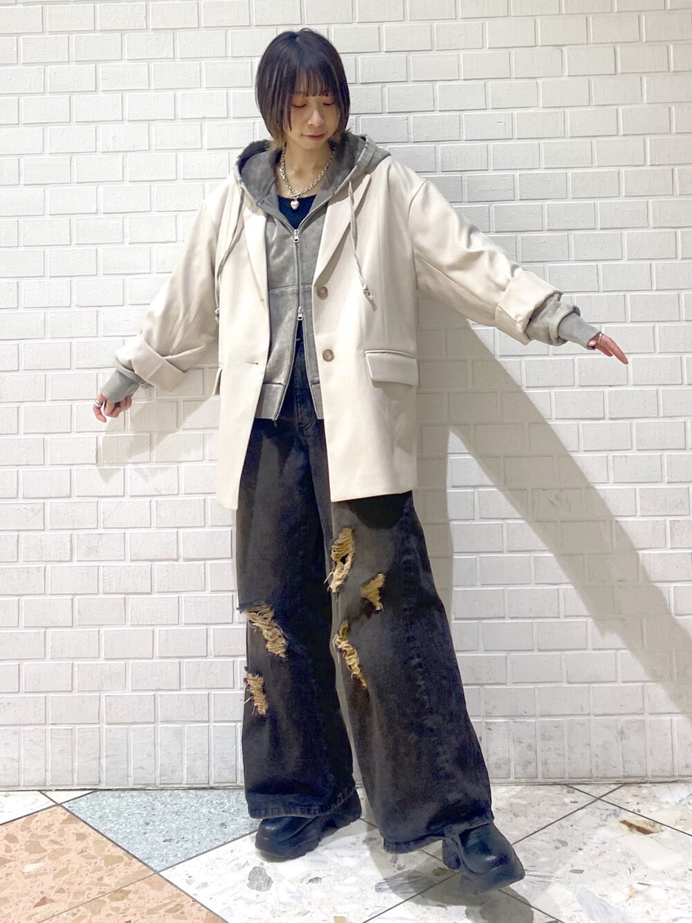 ブラック系のデニムパンツ、ベージュ系のテーラードジャケット、グレー系のパーカーを着用したレディースの冬コーディネートの6枚目の写真