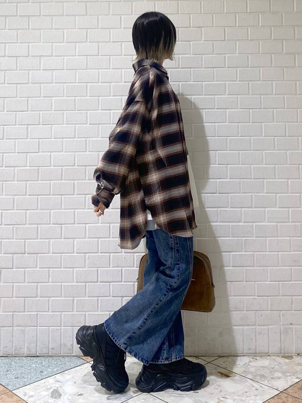 ブラック系のスニーカー、イエロー系のボストンバッグ、ブルー系のデニムパンツを着用したレディースの秋コーディネートの6枚目の写真