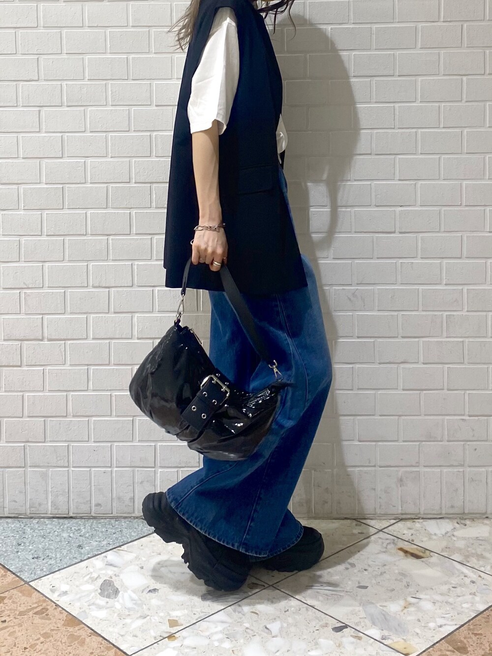 ブルー系のデニムパンツ、ブラック系のスニーカー、ブラック系のショルダーバッグを着用したレディースの秋コーディネートの4枚目の写真