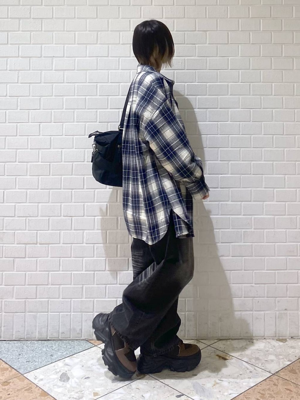 ブラウン系のブーツ、ブラック系のボストンバッグ、ブラック系のデニムパンツを着用したレディースの秋コーディネートの8枚目の写真