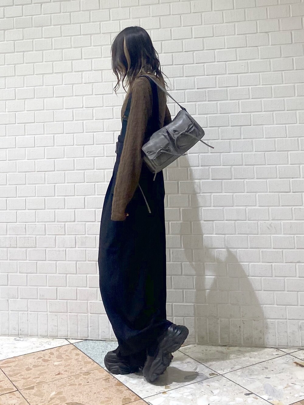 ブラック系のブーツ、ブラック系のスラックス、ブラウン系のTシャツ/カットソーを着用したレディースの秋コーディネートの3枚目の写真