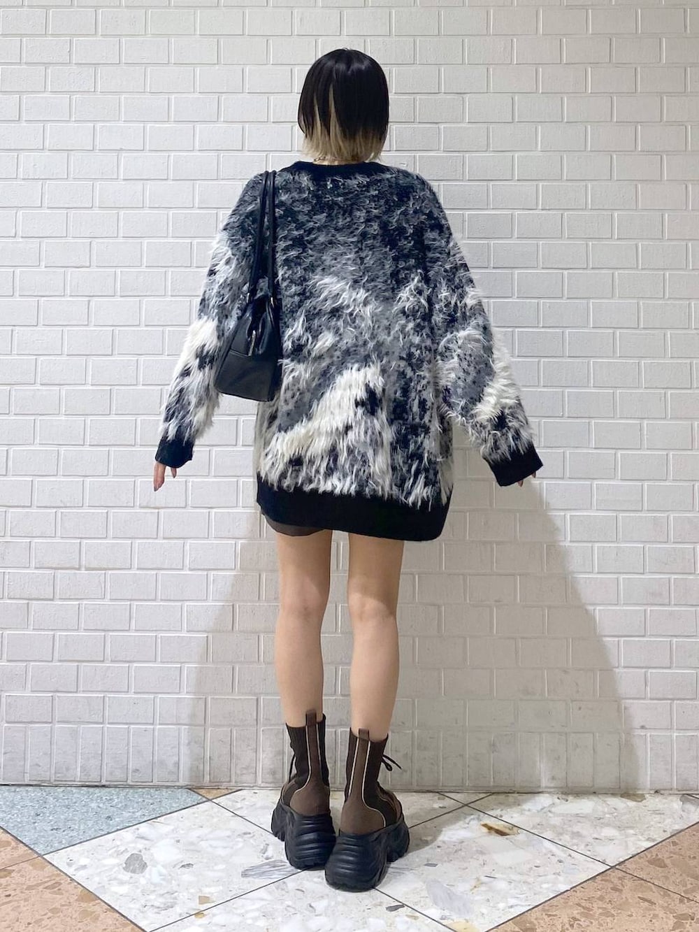 ブラウン系のブーツ、ブラック系のボストンバッグ、レッド系のニット/セーターを着用したレディースの秋コーディネートの6枚目の写真