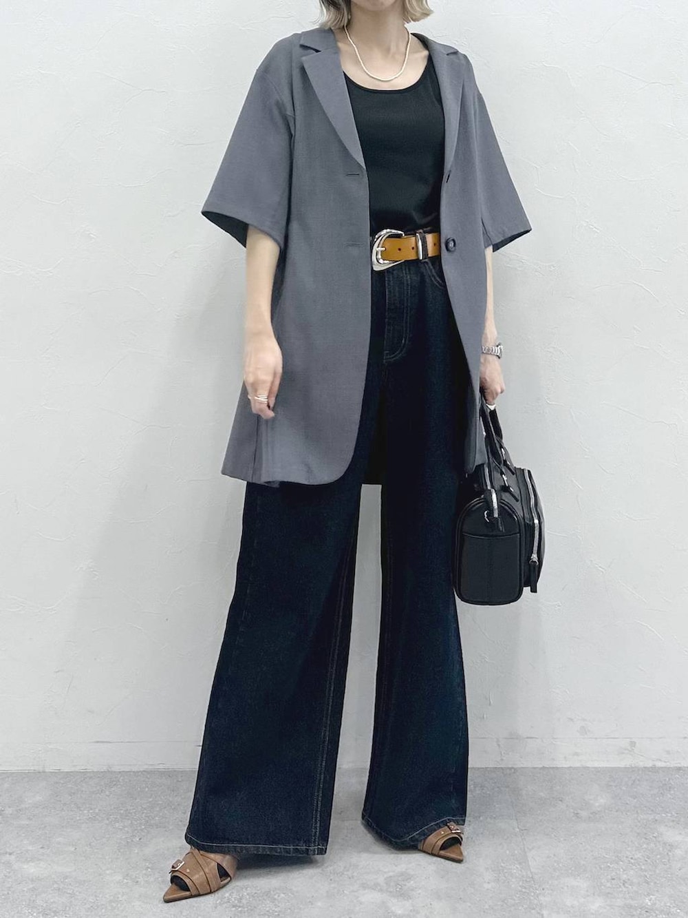 ブラック系のキャミソール、ブルー系のデニムパンツ、ブラック系のショルダーバッグを着用したレディースの春コーディネートの4枚目の写真
