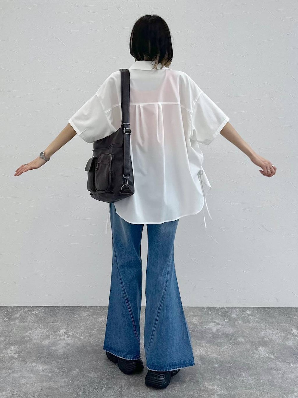 ブルー系のデニムパンツ、ブラック系のショルダーバッグ、グレー系のサンダルを着用したレディースの春コーディネートの6枚目の写真