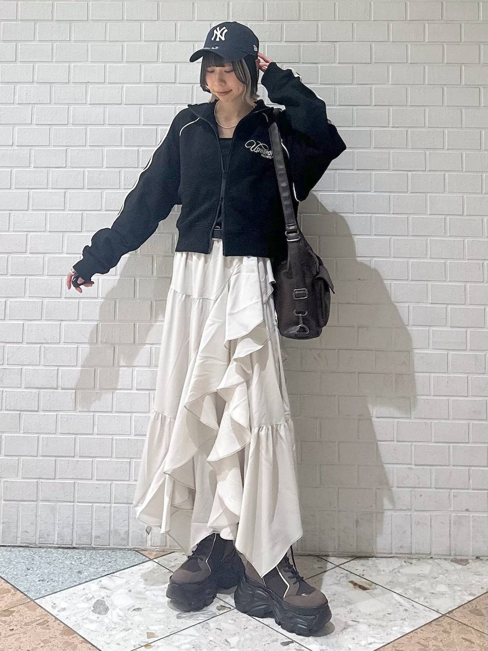 ブラウン系のブーツ、ブラック系のキャミソール、ベージュ系のスカートを着用したレディースの春コーディネートの3枚目の写真