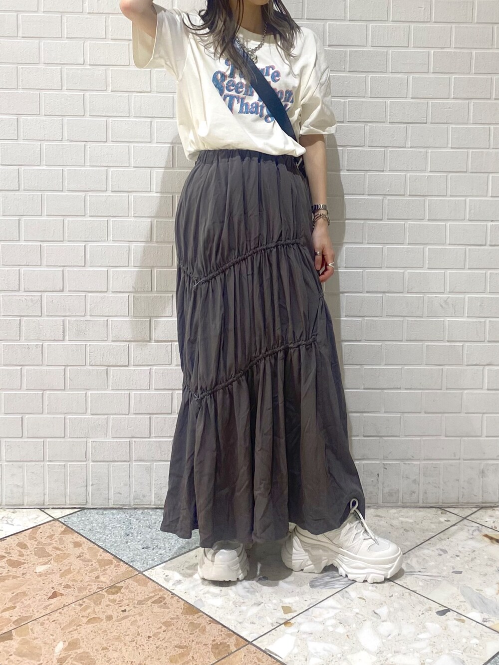 ホワイト系のスニーカー、ブラック系のショルダーバッグ、ベージュ系のTシャツ/カットソーを着用したレディースの夏コーディネートの4枚目の写真