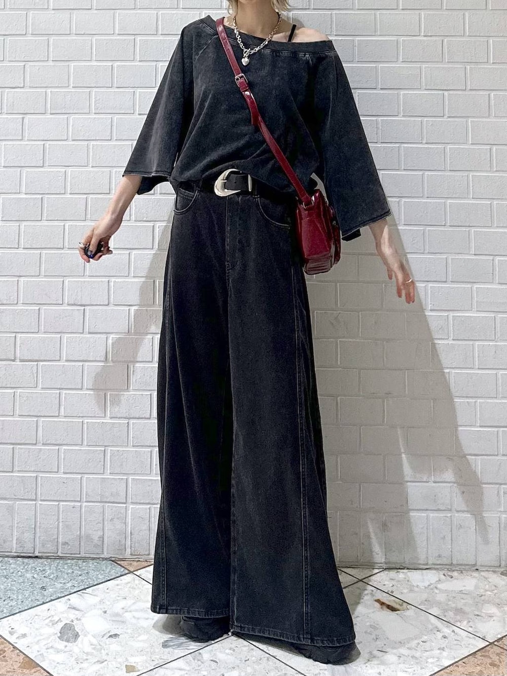 ブラック系のデニムパンツ、ブラック系のTシャツ/カットソー、レッド系のショルダーバッグを着用したレディースの夏コーディネートの3枚目の写真