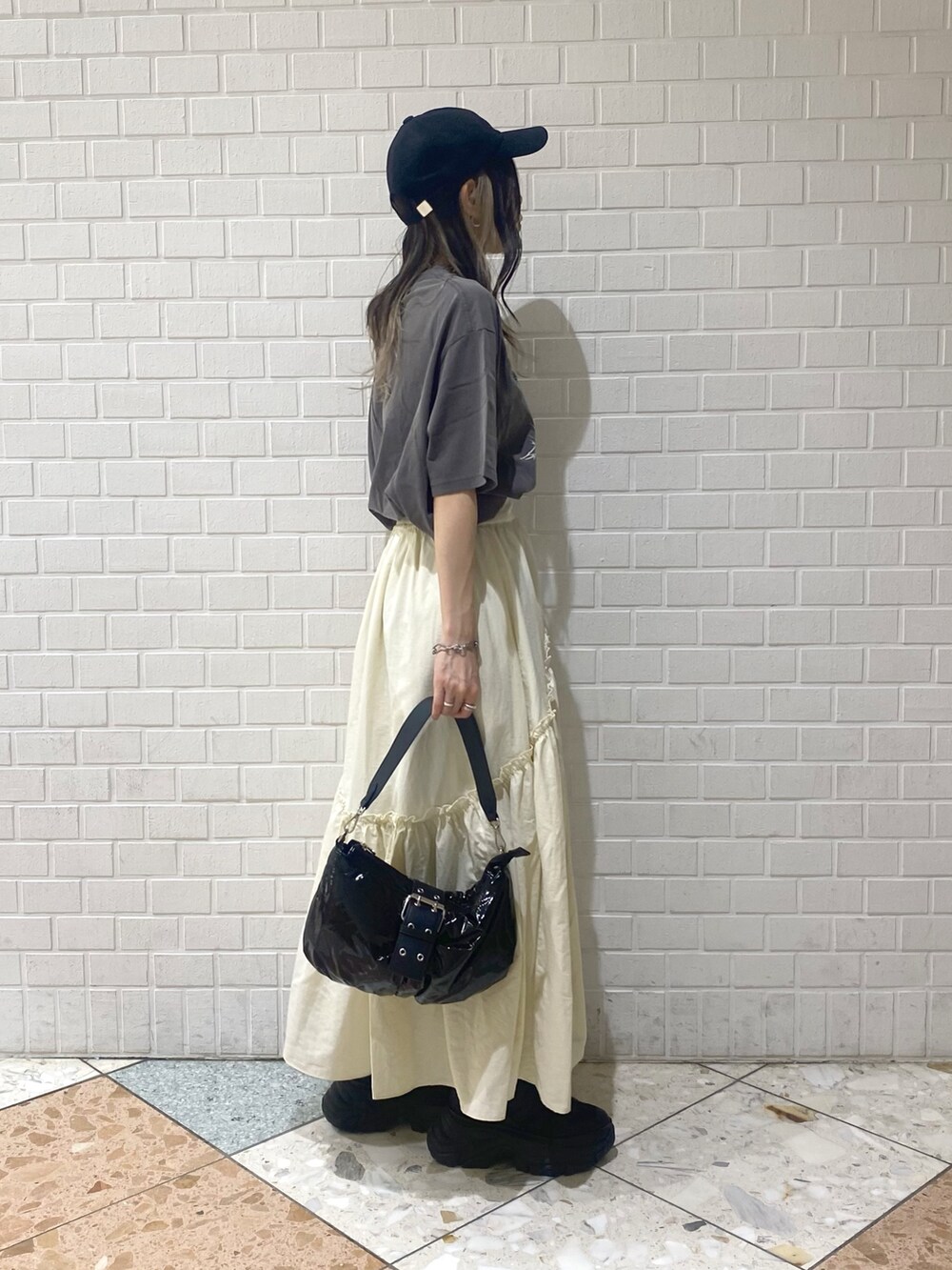 ブラック系のショルダーバッグ、ブラック系のスニーカー、ホワイト系のスカートを着用したレディースの夏コーディネートの6枚目の写真