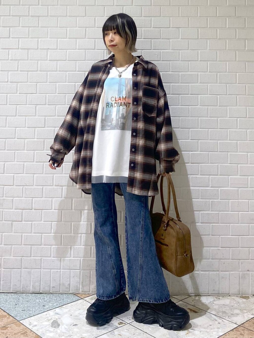 ブラック系のスニーカー、イエロー系のボストンバッグ、ブルー系のデニムパンツを着用したレディースの秋コーディネートの8枚目の写真