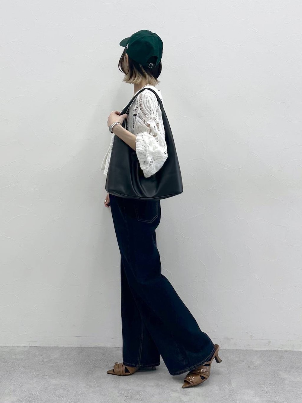 ブラック系のキャミソール、ホワイト系のカーディガン/ボレロ、ブルー系のスラックスを着用したレディースの春コーディネートの5枚目の写真