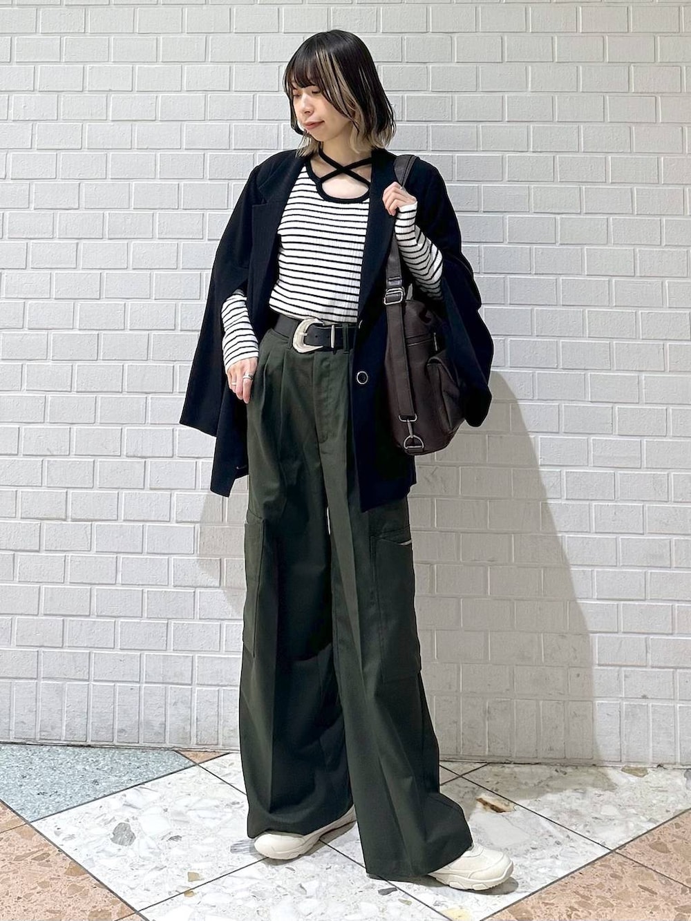 ブラック系のテーラードジャケット、ホワイト系のスニーカー、グリーン系のスラックスを着用したレディースの冬コーディネートの2枚目の写真