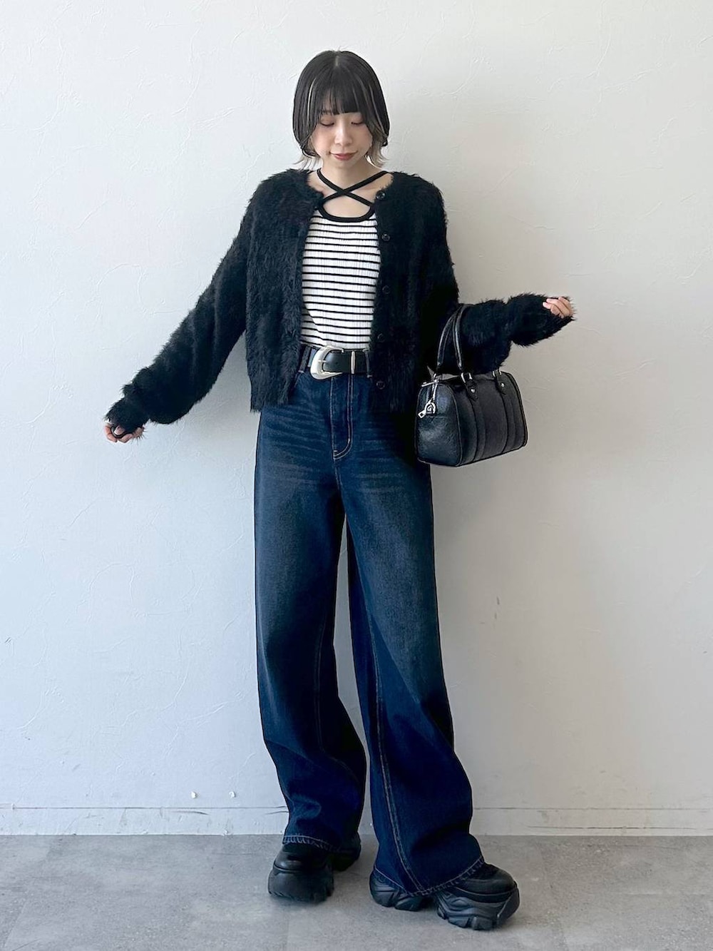 ブラック系のブーツ、ブルー系のスラックス、ブラック系のボストンバッグを着用したレディースの冬コーディネートの3枚目の写真