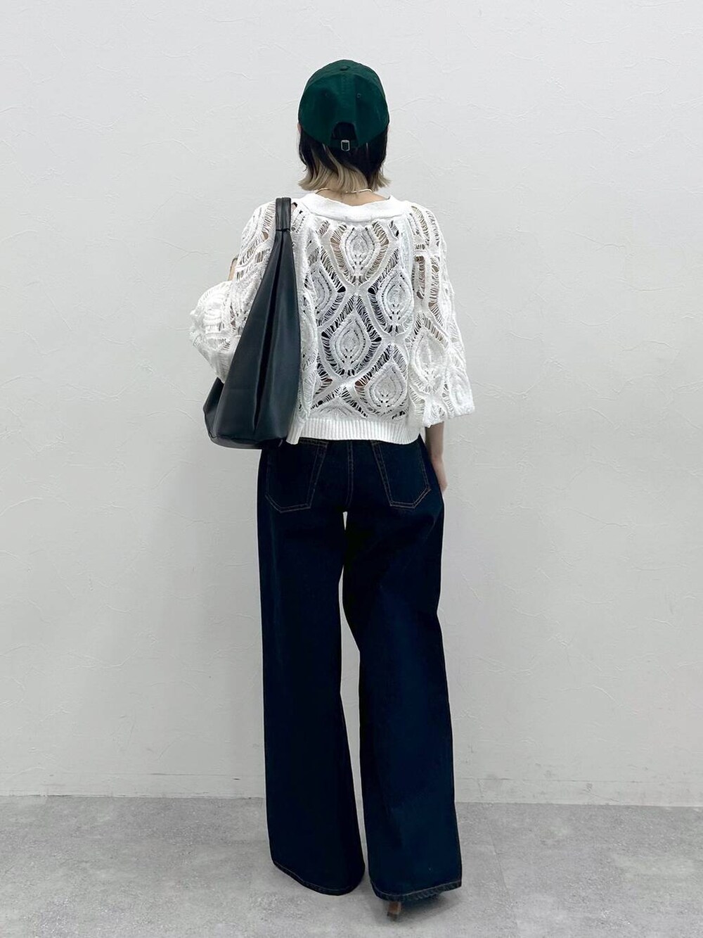 ブラック系のキャミソール、ホワイト系のカーディガン/ボレロ、ブルー系のスラックスを着用したレディースの春コーディネートの7枚目の写真